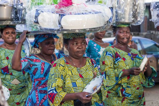 Un groupe de femmes portant sur leurs têtes des cadeaux emballés.