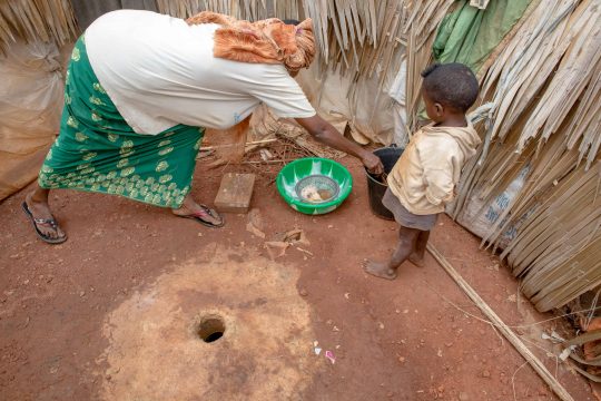 Une femme avec un enfant dans une toilette du Camp de réfugiés au Cameroun