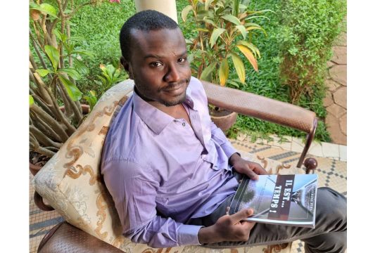 Souleymane Hima est assis tenant son ouvrage intitulé " IL EST TEMPS"