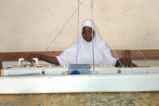 Maimouna Issa travaillant sur sa machine de tricotage