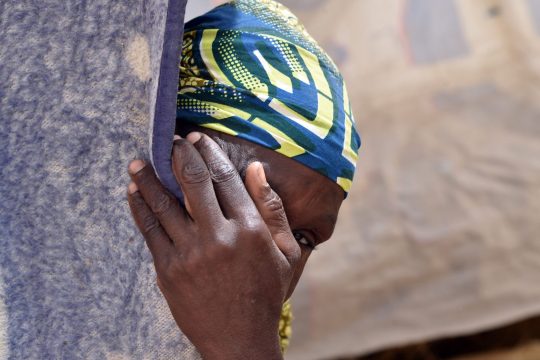 Une femme se cache derrière un rideau d'une tente de fortune dans un camp du village de Kidjendi près de Diffa le 19 juin 2016.