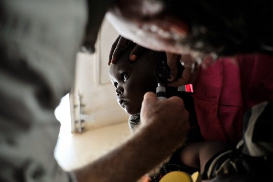 L'oreille d'un bébé est examinée pour une infection dans une clinique de Mogadiscio, en Somalie. Lors d'une clinique tenue au camp d'entraînement de Jazeera le 6 avril, les patients se rendent dans une clinique médicale gratuite afin de recevoir un traitement pour diverses maladies. De nombreux patients de la clinique viennent du camp de personnes déplacées de Jazeera à proximité, où il existe encore une importante communauté de déplacés internes somaliens. AU UN IST PHOTO / TOBIN JONES.