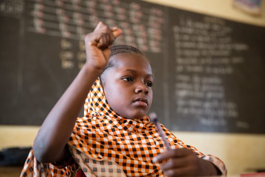 Une élève lève la main en classe