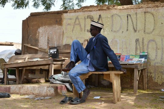 Une personne assise sur un banc écoutant sa radio à Niamey / Crédit : Anne Mimault pour Studio Kalangou