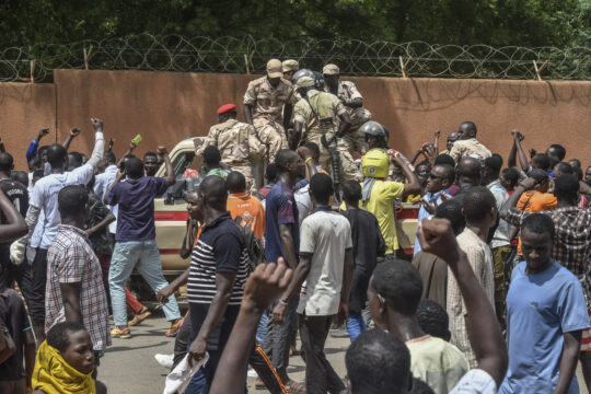 Des manifestants applaudissant des militaires alors qu'ils se rassemblent devant l'ambassade de France à Niamey lors d'une manifestation qui a suivi un rassemblement de soutien à la junte nigérienne à Niamey le 30 juillet 2023 / AFP