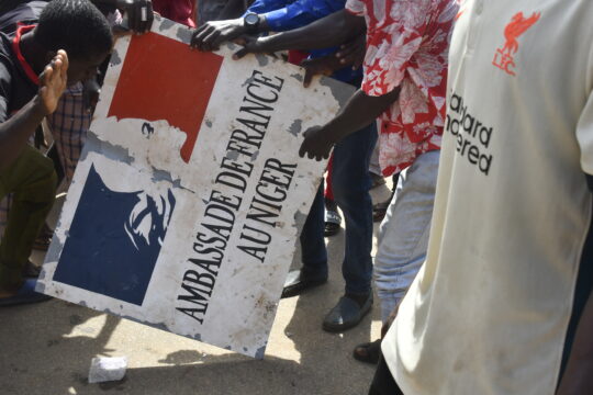 Des manifestants brandissant une pancarte prise à l'ambassade de France à Niamey lors d'une manifestation qui a suivi un rassemblement de soutien à la junte nigérienne à Niamey le 30 juillet 2023 /NIAMEY, NIGER/ AFP