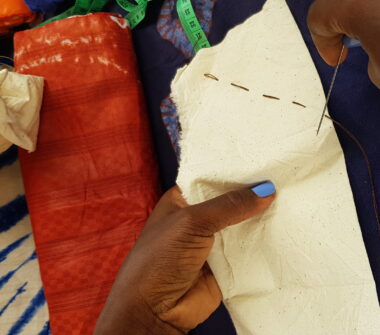 Une femme en train de coudre un tissu / Photo par sandraidossou via iwaria.com