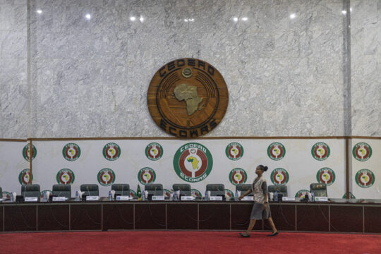 Un membre du personnel de la CEDEAO passant devant le podium officiel avant une conférence de presse organisée par le Commonwealth au siège de la CEDEAO à Abuja le 27 février 2023 / Photo par MICHELE SPATARI / AFP